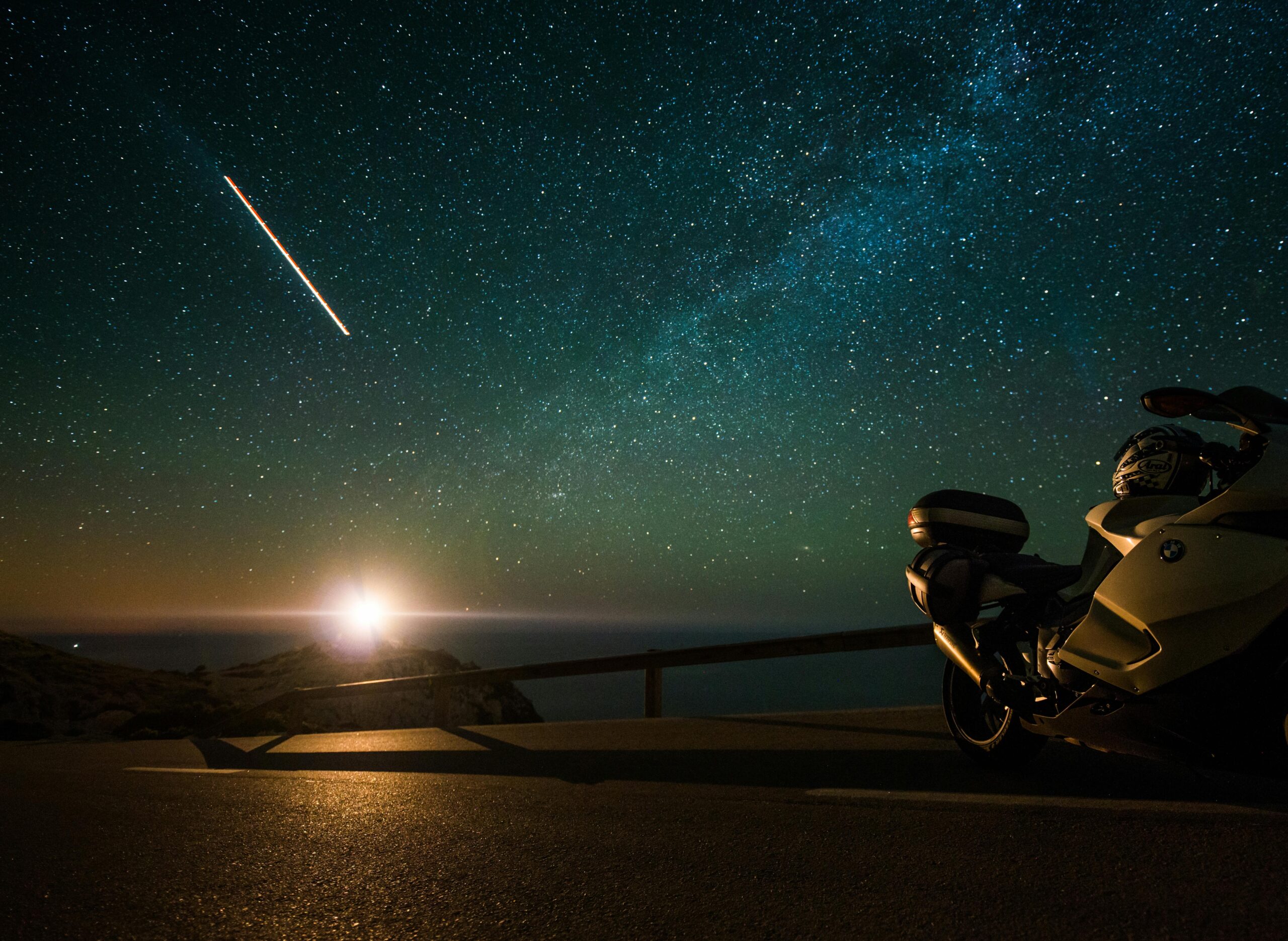 A scenic motorcycle parked under a starry night sky with the Milky Way overhead, capturing travel and adventure.
